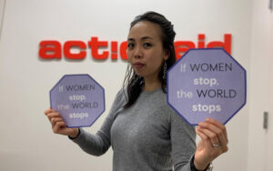 Woman in front of ActionAid logo holding signs