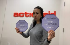 Woman in front of ActionAid logo holding signs