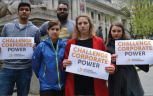 Several people holding Corporate Accountability posters